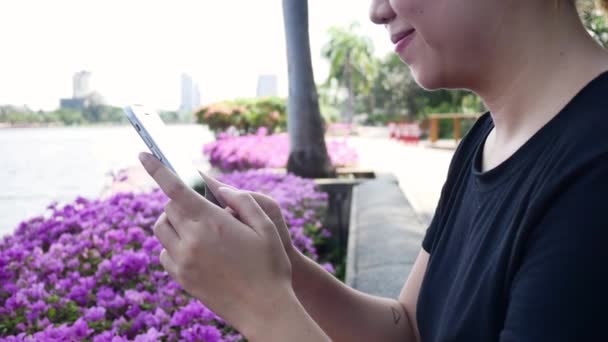 Bella Asiatica Giovane Donna Seduta Alla Panchina Nel Parco Utilizzando — Video Stock