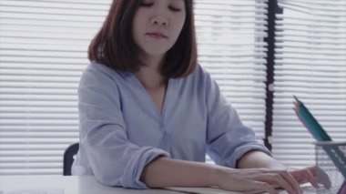 Evde oturma odasında otururken dizüstü bilgisayarda çalışma güzel genç gülümseyen Asyalı kadın. Ev ofisinde çalışmak için telefon kullanarak Asya iş kadını. Evde zaman zevk.