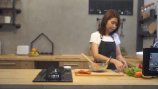 年轻的亚洲妇女在厨房录制视频摄像机 微笑的亚洲妇女工作在食物博主概念在厨房的水果和蔬菜 — 图库视频影像