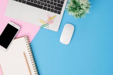 Ofis Resepsiyon çalışma alanı - düz üstten görünüm mockup fotoğraf çalışma alanı laptop ile alay smartphone ve boş defter pastel arka plan üzerinde yatıyordu. Mavi pembe renkli arka plan çalışma Resepsiyon kavramı.