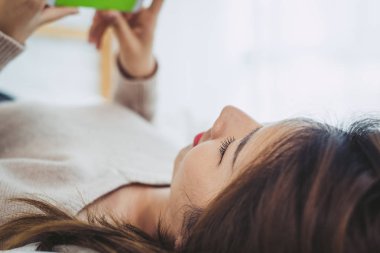 Mutlu Asyalı kadınlar akıllı telefon sabah yatakta kullanıyorsunuz. Asyalı kadın yatakta smartphone ile sosyal uygulamalar kontrol. Gülümseyen kadın evde cep telefonu ile net sörf. Telefon bağımlısı kavramı. 