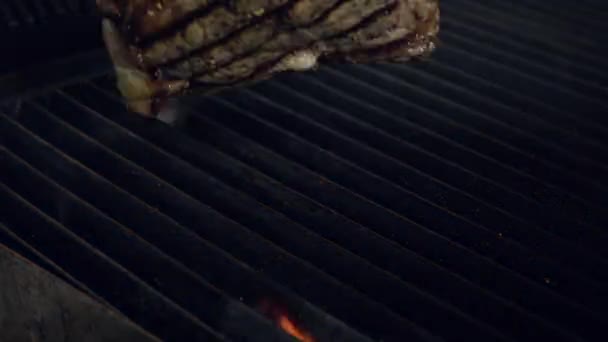 料理長を履いて金属鉗子を使用して下に火が付いてホット喫煙グリル調理肉の部分 近くにはスローモーション — ストック動画
