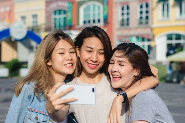 Attractive beautiful asian friends women using a smartphone. Happy young asian teenage at urban city while taking self portraits with her friends together with a smartphone.