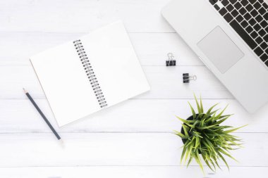 En az çalışma alanı - yaratıcı düz fotoğraf çalışma masası yatıyordu. Beyaz ahşap arka plan üzerinde bitki ve görünümü ofis büro dizüstü bilgisayar ile alay dizüstü kadar top. Kopya alanı, düz yatıyordu fotoğraf ile Üstten Görünüm
