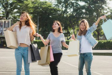Grup genç Asyalı kadın açık bir pazarda alışveriş torbaları ellerinde ile alışveriş. Genç kadın sıcak güneş ışığı altında alışveriş torbasında marifetlerini göster. Grup açık alışveriş kavramı.
