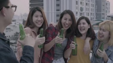 Yavaş hareket - Grup Genç Asyalı kadınlar ve dans ve çatıda günbatımı kentsel partide dj tarafından oynanan hava müzik kadar kollarını yükselterek insanlar. Genç Asyalı arkadaşlar içecekler bira ile takılmak.