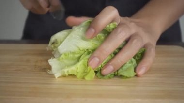 Yavaş hareket - salata sağlıklı yemek yapma ve marul mutfak kesme tahtası üzerinde doğrama Şef kadının yakın.