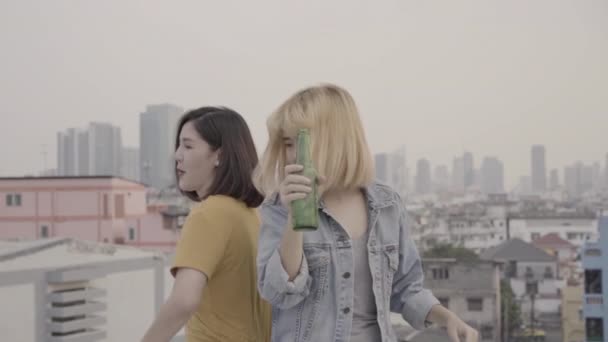 慢动作小组年轻的亚洲妇女人们跳舞 举起双臂 在屋顶上的日落城市派对上 演奏的音乐 年轻的亚洲女孩朋友一起喝酒喝啤酒 — 图库视频影像