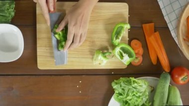 Salata sağlıklı yemek yapma ve dolmalık biber kesme tahtası mutfakta doğrama kadın baş üstten görünüm.