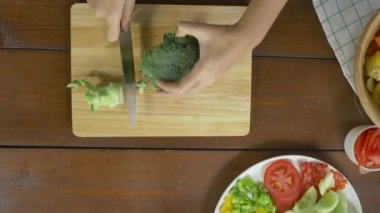 Salata sağlıklı yemek yapma ve brokoli kesme tahtası mutfakta doğrama kadın baş üstten görünüm.