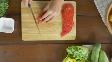 Salata sağlıklı yemek yapma ve mutfakta kesme tahtası üzerinde domates doğrama kadın baş üstten görünüm.
