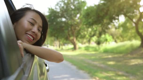 Jeune femme asiatique appréciant sentir le vent par la fenêtre de la voiture .