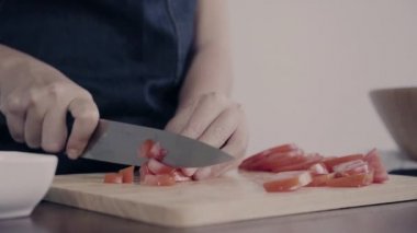 Salata sağlıklı yemek yapma ve mutfakta kesme tahtası üzerinde domates doğrama Şef kadının yakın çekim.