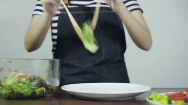 Lezzetli organik yeşil salata savurma sağlık bilinçli genç şef kadın yakın çekim.