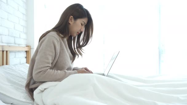 Bonita Jovem Sorrindo Mulher Asiática Trabalhando Laptop Enquanto Sentado Cama — Vídeo de Stock