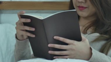 Evde rahat giyim kitap zevk okuma yatakta yalan zevk yaşam tarzı mutlu genç Asyalı kadın. Yaşam tarzı kadın kavramı rahatlatıcı.