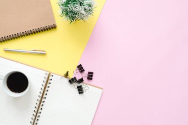 Yaratıcı düz fotoğraf çalışma masası yatıyordu. Üstten Görünüm Ofis Masası sahte kadar dizüstü bilgisayarlar, bitki, pastel renkli arka plan üzerinde kahve Kupası ve kopya alanı ile. Kopya alanı, düz yatıyordu fotoğraf ile Üstten Görünüm.