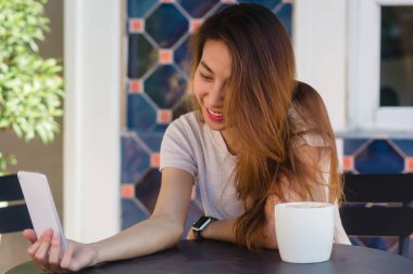 Café'de bir akıllı telefon kullanarak bir selfie alarak çekici güzel mutlu genç Asyalı kadın. Genç Asyalı kız kendi kendine portre alarak restoranda.