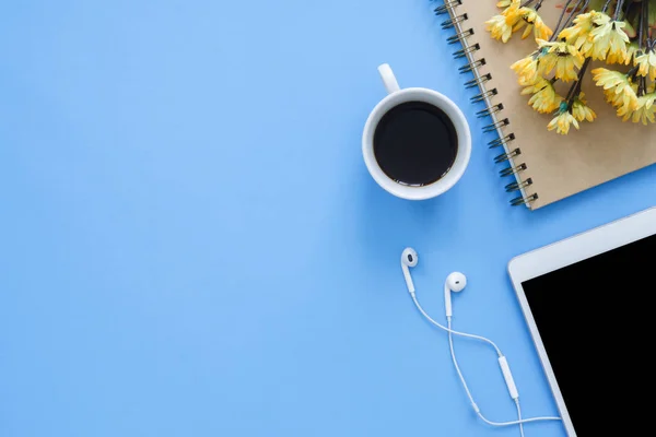 Office desk working space - Flat lay top view mockup photo of working space with smart device, coffee cup and notebook on blue pastel background. Pastel blue color copy space working desk concept.