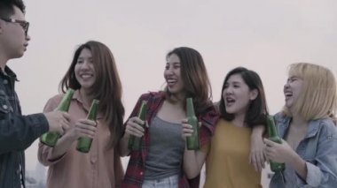 Yavaş hareket - Grup Genç Asyalı kadınlar ve dans ve çatıda günbatımı kentsel partide dj tarafından oynanan hava müzik kadar kollarını yükselterek insanlar. Genç Asyalı arkadaşlar içecekler bira ile takılmak.