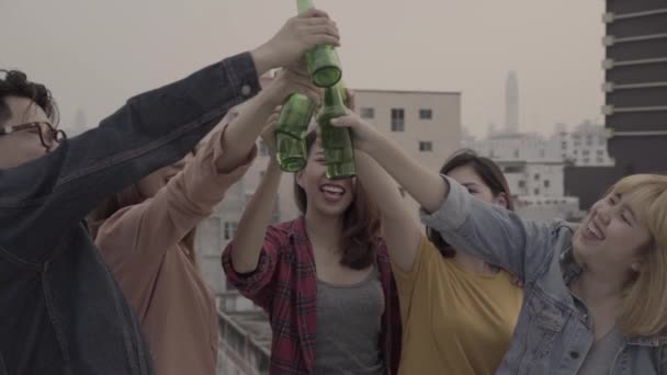 慢动作 一群年轻的亚洲妇女和男子跳舞和举起他们的手臂在空中音乐 在日落城市党在屋顶上播放 年轻的亚洲朋友一起喝酒喝啤酒 — 图库视频影像