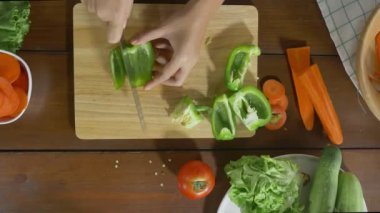 Salata sağlıklı yemek yapma ve dolmalık biber kesme tahtası mutfakta doğrama kadın baş üstten görünüm.