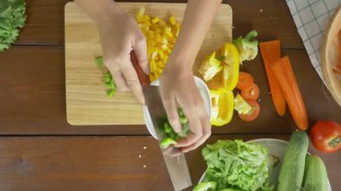Salata sağlıklı yemek yapma ve dolmalık biber kesme tahtası mutfakta doğrama kadın baş üstten görünüm.