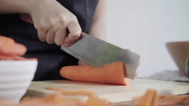 Salata sağlıklı yemek yapma ve mutfakta kesme tahtası üzerinde havuç doğrama Şef kadının yakın çekim.