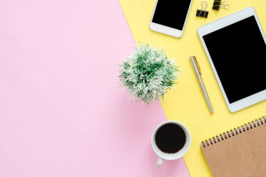 Ofis Masası adlı kullanıcının alanı - düz çalışma boş defter sayfası, kahve fincanı ve sahte telefon tablet pastel arka plan üzerinde yukarı çalışma alanının en iyi görünümü yatırın. Pastel pembe sarı renk arka plan boşluk kavramı.