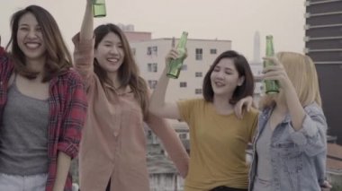 Yavaş hareket - dans ve müzik havada kollarını kadar yükselterek Grup Genç Asyalı kadınlar kişi çatıda günbatımı kentsel partide dj tarafından oynanır. Genç Asyalı kız arkadaş içecekler bira ile takılmak.