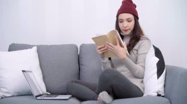 Güzel Asyalı kadın kanepe oturma odasında yatan süre bilgisayar ya da laptop oynamak. Mutlu kadın evde alışveriş online satın alma. Kadın açık ve evde kitap okurken.