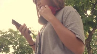 Şehirde bir akıllı telefon üzerinde müzik dinlemek güzel genç Asyalı kadın. Sokakta müzik dinlemek rahatlatıcı Genç Asyalı kadın.