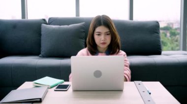 Genç Asyalı kadın araştırma çalışmaları için onu iş yapıyor. Online alışveriş web sitesi tarama yaparken rahatlatıcı kanepede oturan kadın gülümsüyor. Mutlu kız evde serbest zaman sırasında internet üzerinden tarama.