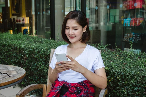 Munter Asiatisk Ung Kvinne Som Sitter Kafeen Med Smarttelefon Snakke – stockfoto