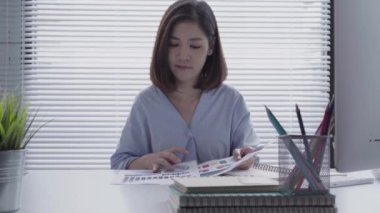 Evde oturma odasında otururken dizüstü bilgisayarda çalışma güzel genç gülümseyen Asyalı kadın. Ev ofisinde çalışan Asya iş kadın. Evde zaman zevk.