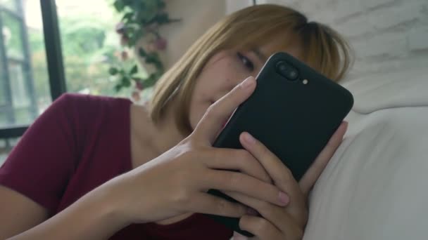 Donna Asiatica Che Gioca Smartphone Mentre Trova Sul Divano Casa — Video Stock