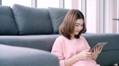 Asyalı kadın ev kanepe oturma odasında yatarken tablet kullanma. Mutlu erkek onun arkadaş veya erkek evde ile görüntülü görüşme için tablet kullanmak.