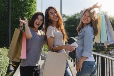 Genç Asyalı kadın ellerinde alışveriş torbaları ile açık bir pazarda alışveriş grubudur. Genç Asyalı kadınlar sıcak güneş ışığı altında alışveriş torbasında marifetlerini göster. Grup açık alışveriş kavramı.