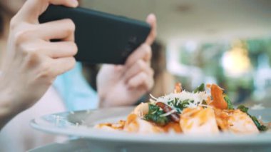 Kadın blogger telefonunu restoranda öğle fotoğraf çekme. Spagetti yemek yemek Mobil kamera ile fotoğraf çekme Smartphone cep telefonu ile bir genç kadın alarak fotoğraf.