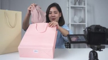 Marka ya da onun abone mutlu güzel Asyalı kadın unboxing hediyesi. Kadın blogger kayıt fliming unboxing bir video kameradan video.