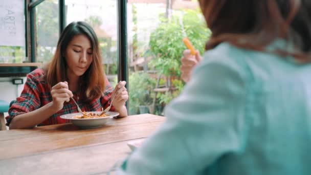 美丽快乐的亚洲女同性恋同志夫妇坐在一边吃着一盘意大利海鲜面条和法式薯条在餐馆或咖啡馆 而微笑着看食物 — 图库视频影像