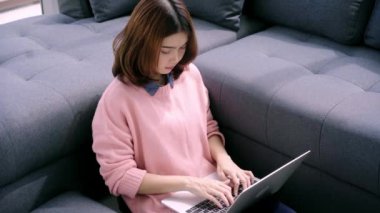 Genç Asyalı kadın araştırma çalışmaları için onu iş yapıyor. Online alışveriş web sitesi tarama yaparken rahatlatıcı kanepede oturan kadın gülümsüyor. Mutlu kız evde serbest zaman sırasında internet üzerinden tarama.