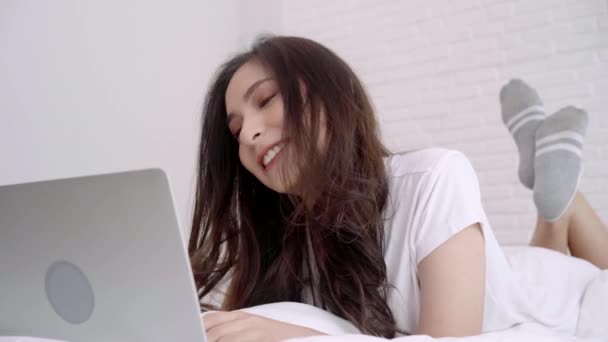 美しいアジアの女性は 彼女の寝室のベッドの上に横たわっている間コンピューターまたはラップトップを再生します 幸せな女性のオンライン ショッピングを自宅を購入します ホーム コンセプトのライフ スタイル女性 — ストック動画