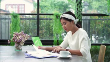 Evde oturma odasında otururken dizüstü bilgisayarda çalışma güzel genç gülümseyen Asyalı kadın. Belge finans ve hesap makinesi ev ofisinde çalışan Asya iş kadın. Evde zaman zevk.