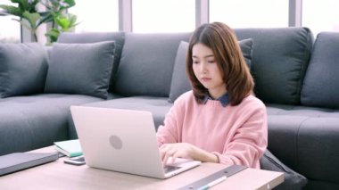 Laptop oturma kanepe evde oturma odasında uyku tadını çıkarırken çalışan güzel genç gülümseyen Asyalı kadın. Mutlu kadın evde alışveriş online satın alma. Yaşam tarzı kadına ev concept.