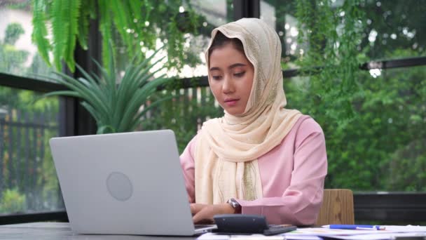 美しい若い笑顔アジア イスラム教徒女性の自宅のリビング ルームに座っているラップトップに取り組んで アジア ビジネスの女性は 作業文書金融とホーム オフィスの計算機 家での時間を楽しんでください — ストック動画