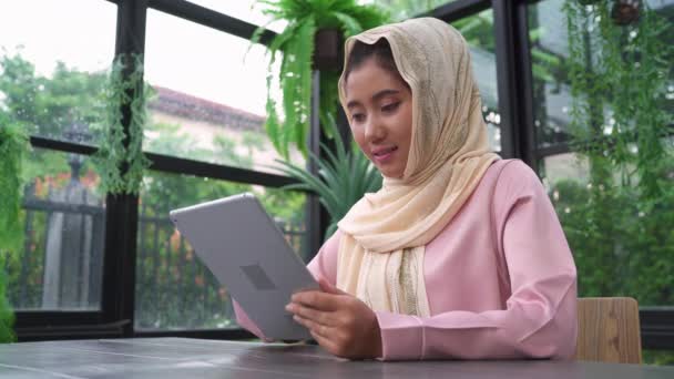 Bonito Jovem Sorrindo Asiático Muçulmano Mulher Usando Tablet Sentado Sala — Vídeo de Stock