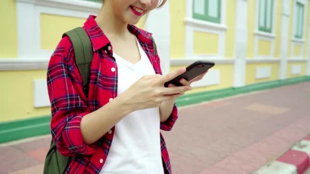 亚洲女子旅游背包客微笑着 使用智能手机独自旅行假日户外在城市街道在曼谷 — 图库视频影像