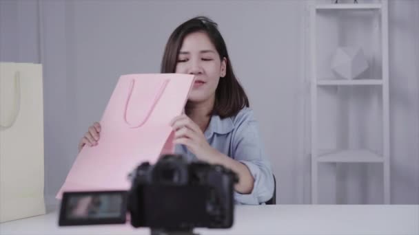 美しいアジアの女性の幸せなブランドまたは彼女の加入者からボックス化解除の贈り物 トリップ ボックス化解除のビデオをカメラからビデオ女性ブロガーの記録 — ストック動画