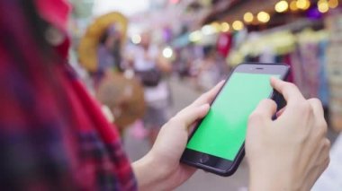 Gülümseyen ve yalnız tatil açık havada şehir sokak Khao San Road, Bangkok Bangkok - Tayland seyahat eden yeşil ekran smartphone kullanarak Asyalı kadın turist backpacker.